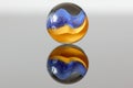 Yellow and blue marble on a white surface with a reflection - stock photo Royalty Free Stock Photo