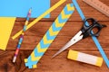 Yellow and blue paper bookmark. Scissors, glue stick, colored paper sheets, ruler, pencil on a wooden table. Light paper art Royalty Free Stock Photo