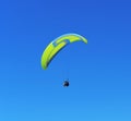 Yellow blue paraglider on blue sky.