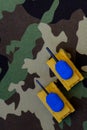 Yellow-blue tanks figures on camouflage background, Ukrainian flag colors on toy tank figures, anti-war concept Royalty Free Stock Photo