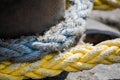 Yellow and blue thick sea ropes tied around bitt