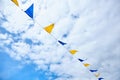 Yellow and blue triangular festival flags on sky background with white clouds. Outdoor Celebration Party. Festive Royalty Free Stock Photo