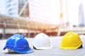 Yellow, blue and white hard safety wear helmet hat in the project at construction site building on concrete floor on city.