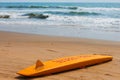 The yellow board of the rescuer for surfing lies on the sand used by the lifeguard working on the Arambol beach Royalty Free Stock Photo