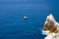 Yellow boat on blue dark water of Grotta di Lord Byron near coast with rock cliff, Portovenere town, Ligurian sea, Riviera di Leva