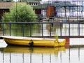 A yellow boat, a deciduous tree and approaches rafts on a swollen river