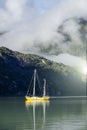 Yellow boat floating on the water on foggy morning day in the mountains Royalty Free Stock Photo