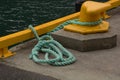 Yellow bollard harbor on boat pier with green sea rope Royalty Free Stock Photo