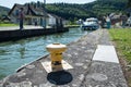 A yellow bollard at the Lutzelbourg lock in the Marne-Rhine Canal with ship out of focus in background entering the lock