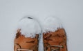Yellow boots on a wooden road in winter. Vintage pair of yellow working and trekking boots, stepping on snow-covered surface