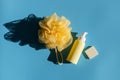 Yellow bottle with dispenser, washcloth and bar of soap on blue.