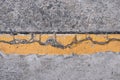 A yellow boundary line on the cracked concrete road