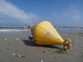 A yellow bouy brought to shore by the sea