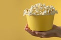 A yellow bowl contains fresh popcorn on a matching yellow background. Copy space. Royalty Free Stock Photo