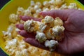 Yellow bowl full with popcorn close-up. Lots of popcorn in women hand.