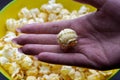 Yellow bowl full with popcorn close-up. One popcorn in women hand.