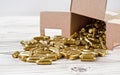 Yellow brass gun ammo spilled from paper carton box on white boar desk - close up