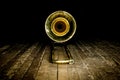 Yellow brass instrument trombone lies on the wooden floor of the stage. front view on the bell