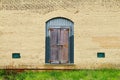 yellow brick building green boarded up door grass rusted