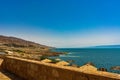 Yellow brick fence against a sandy beach, mountains, sea and blue sky