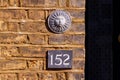 House number 152 on a brick wall under a round sun ornament Royalty Free Stock Photo