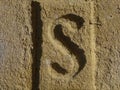 Yellow brick wall macro closeup of special stamped brick with letter S