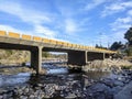 Yellow bridge over the river with rocks under a blue sky