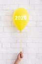 Yellow bright balloon with 2020 white text in woman hand