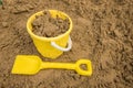 Yellow bucket and spade in the sand, ready to make sandcastles in the sun