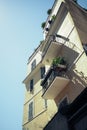 Yellow building with balconies and plants against blue sky