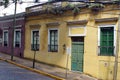 Yellow building with green trim on a shady sidewalk