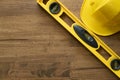 Yellow building level and yellow helmet on the old wood table Royalty Free Stock Photo