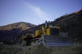 Yellow bulldozer at a construction site with mountains in the background in Arunachal Pradesh