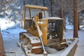 Yellow bulldozer covered with snow abandoned in forest
