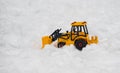 Yellow bulldozer, excavator toy snowplow placed in snow field, a Royalty Free Stock Photo