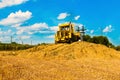 Yellow bulldozer in a field at harvest