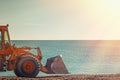 Yellow Bulldozer Rides On The Beach. In The Background Sea And Sky. Light From The Right Side. Copy Space
