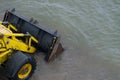 Yellow Bulldozer With A Wheel Drive Lowering Black Metal Blade, Drove Into The Sea In The Coastal Zone Of Shallow Water.