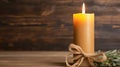 Yellow burning candle on wooden background