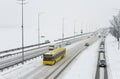 The yellow bus is driving on a snowy road