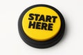 A yellow button with black text start here on a white background encouraging a starting point Royalty Free Stock Photo