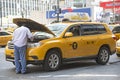 Yellow cab driver looking at engine Royalty Free Stock Photo