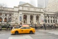 A Yellow Cab Passing Outside Historic Building of Public Library in Manhattan, New York City on a Foggy Day of Winter