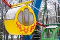 Yellow cabin Ferris wheel against the background of snow covered trees and a residential building, winter Royalty Free Stock Photo