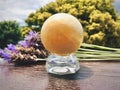 Yellow calcite crystal ball is on a wooden table.