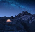 Yellow camping tent on a rocky hill at night