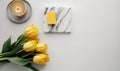 a yellow candle and some yellow tulips on a table