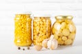 Yellow canned food, canned chickpeas, corn and mushrooms in a glass jar