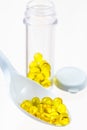 Yellow capsule gel pills on the plastic spoon