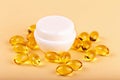 Yellow capsules around a white cosmetic jar Royalty Free Stock Photo